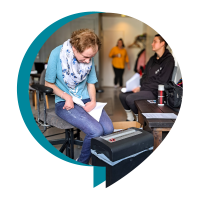 En kvinna som jobbar vid en dokumentförstörare, i bakgrunden två andra kvinnor